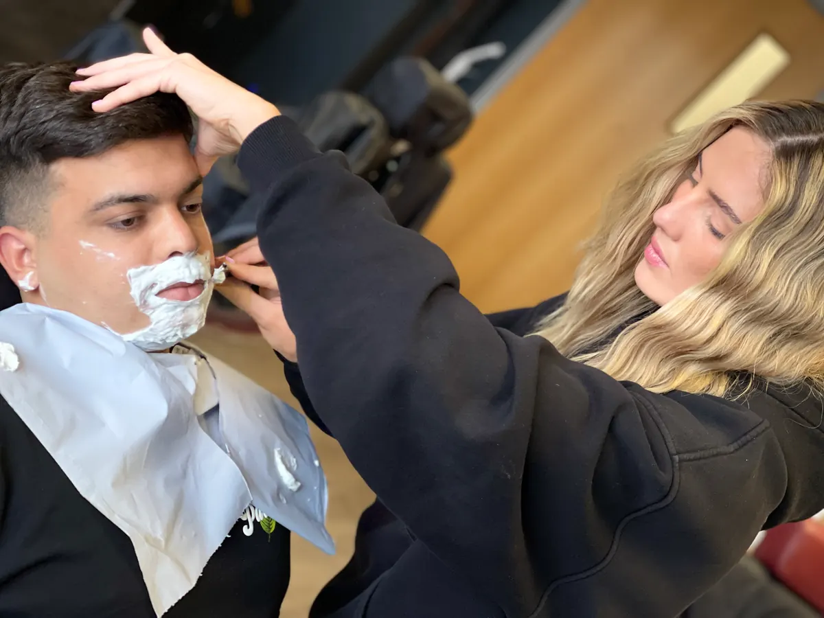 Barber using a razor to shave a client’s face