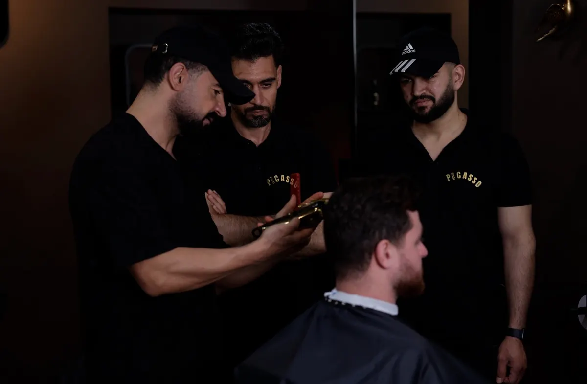 Barber demonstrating clipper cutting while two learners watch